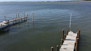 A wooden pier extending into calm water with a boat docked at the end. - Unique & spacious house with boat docks in Tuckerton beach, NJ (Tuckerton)