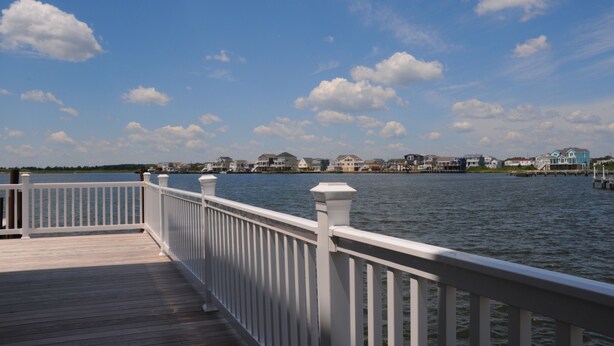 A wooden deck with white railings overlooking a calm body of water. - Unique & spacious house with boat docks in Tuckerton beach, NJ (Tuckerton)