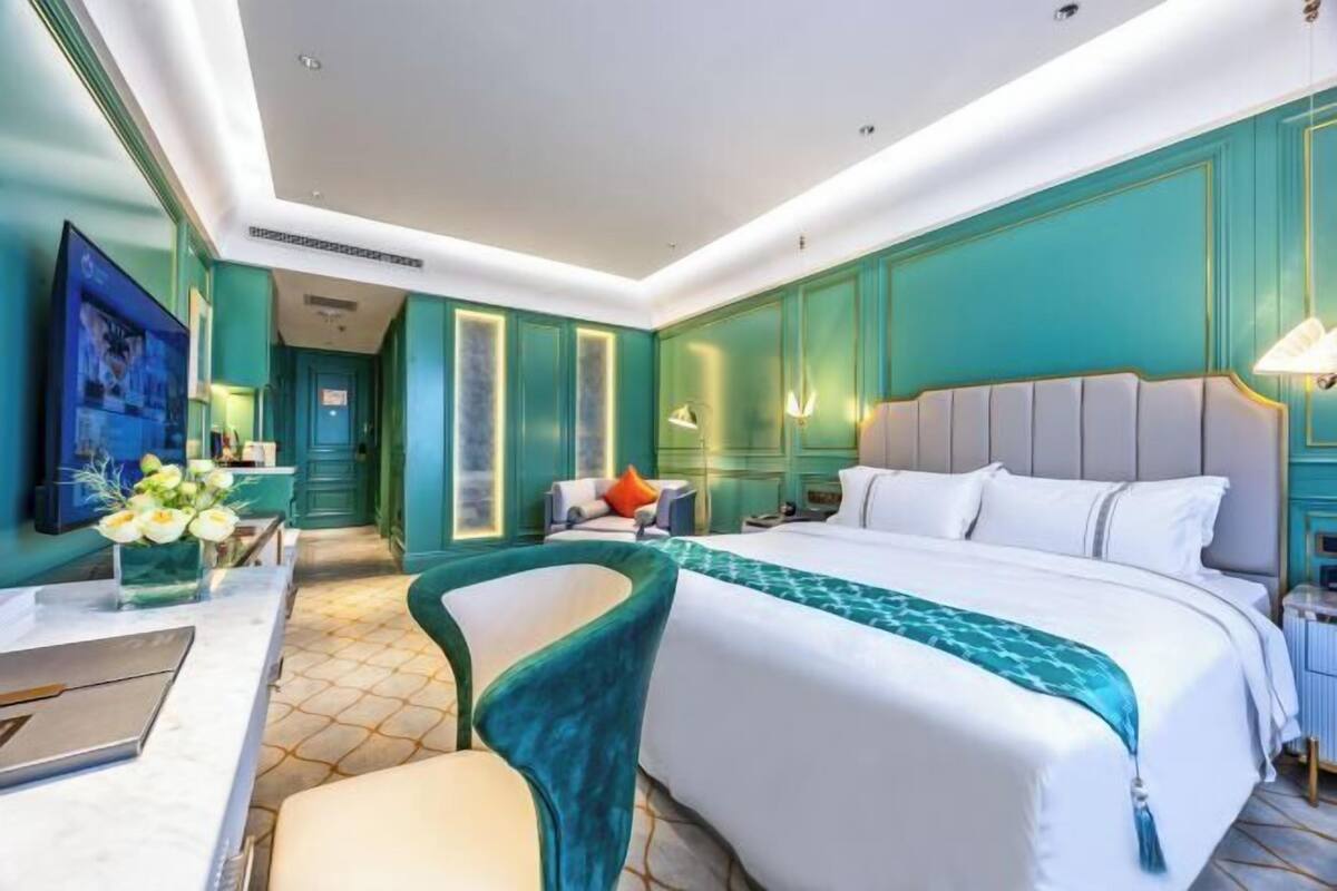 A hotel room with a large bed, a desk, and a chair.