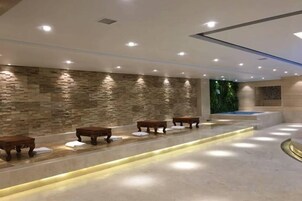 Zona de spa con paredes de piedra, bancos y una recepción.
