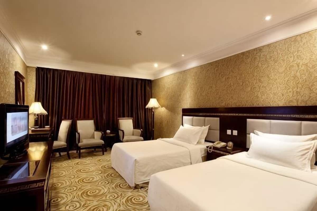 A hotel room with two beds, a TV, a desk, and a chair.