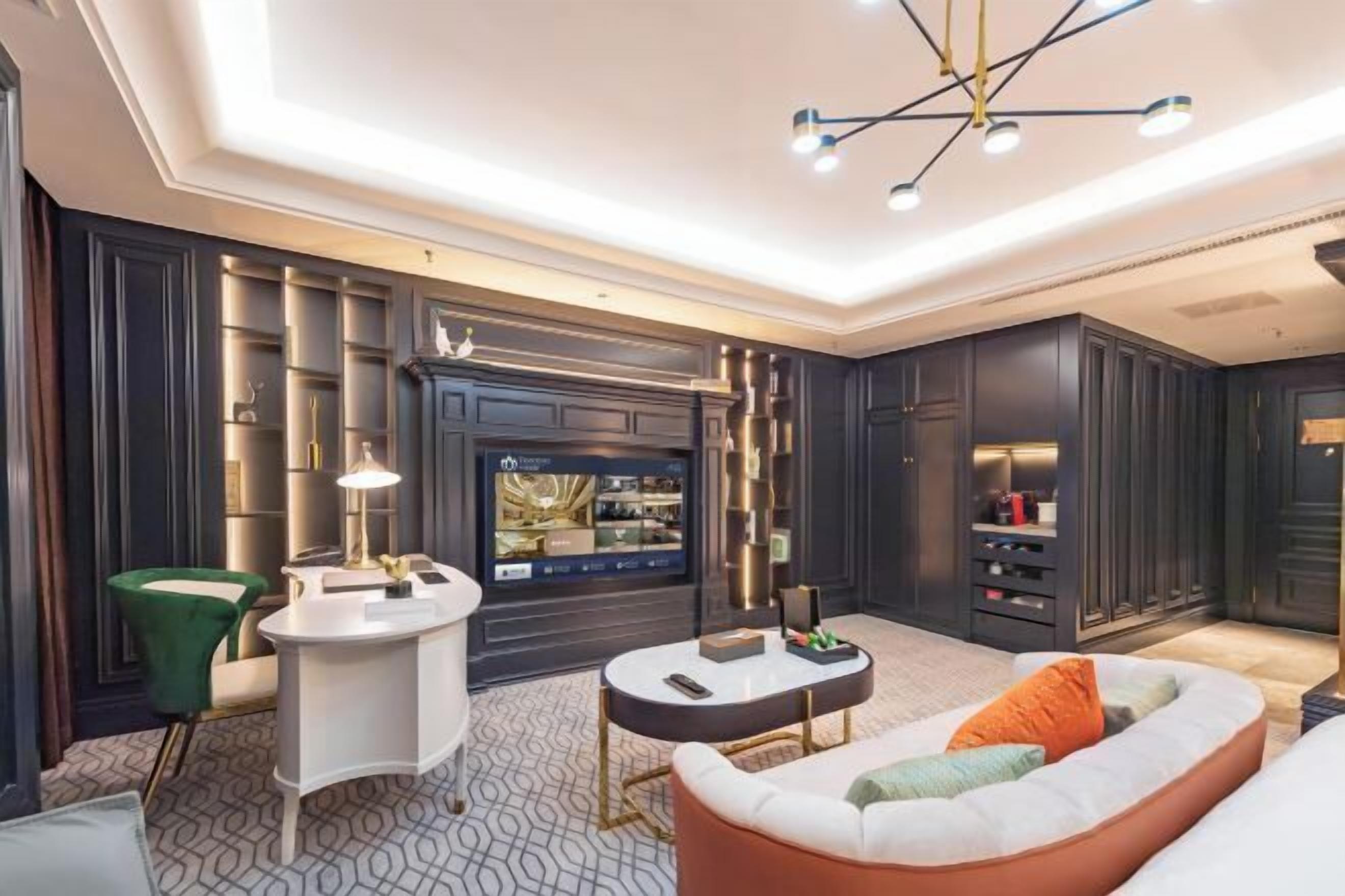 A modern living room with dark wood paneling, a white bar area, a round coffee table, and a green armchair.