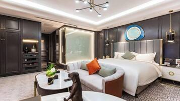 A modern hotel room with a large bed, a sofa, a desk, and a nightstand.