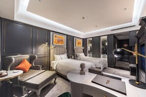 Quarto de hotel moderno com sofá, duas camas, escrivaninha e espelho.