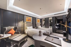 Una habitación de hotel moderna con sofá, dos camas, escritorio y espejo.