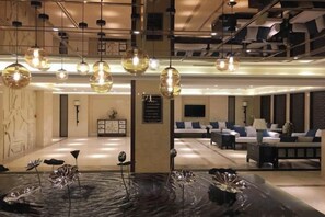 A hotel lobby with a reception desk, seating area, and decorative light fixtures. - Tianxing Hotel (Tieling)
