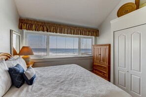 A bedroom with a bed, a window with curtains, a lamp, and a wardrobe.