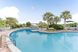 A swimming pool with lounge chairs and palm trees.