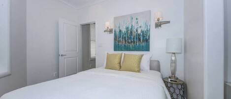 Une chambre à coucher avec un grand lit, un tableau au mur et une lampe de chevet.