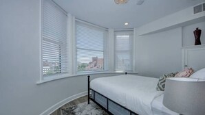 Een slaapkamer met een bed, een raam en een nachtkastje.