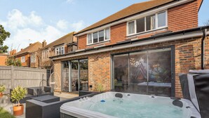 A residential property with a hot tub, outdoor seating, and a large sliding glass door leading to a patio area. - 5 bedroom accommodation in Hove (Hove)
