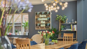 A dining area with a wooden table, blue upholstered chairs, a vase with flowers, and a wall with a motivational poster. - 5 bedroom accommodation in Hove (Hove)