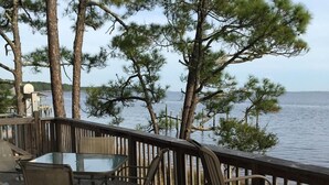 A wooden deck with a glass table and chairs overlooking a body of water. - Amazing Ochlockonee Riverfront Home!  (Panacea)