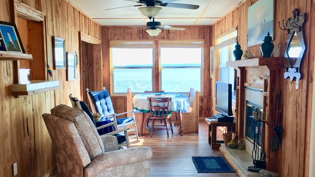 A wooden interior with a sofa, chairs, a dining table, and a fireplace. - Amazing Ochlockonee Riverfront Home!  (Panacea)