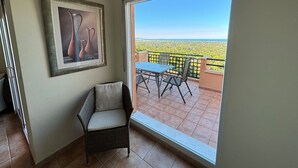 A balcony with a table and chairs, a wicker chair, and a framed picture on the wall. - Beautiful apartment with views (Pedreguer)