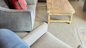 Ein Wohnzimmer mit einem grauen Modulsofa, einem Holztisch und einem blauen Beistelltisch mit Lampe.
