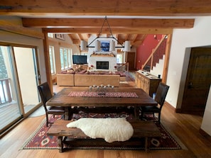A spacious living area with a wooden dining table, sofas, and a fireplace.