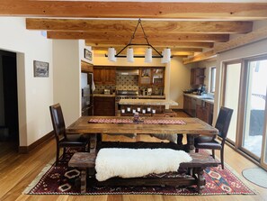 A rustic dining area with a wooden table, benches, and a white fur throw.