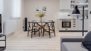 A modern kitchen with a dining area, featuring a round table, chairs, and a vase with flowers. - Retiro Chic - One-bedroom Apartment (Madrid)