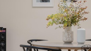 A dining table with a vase of flowers and a white vase, surrounded by chairs. - Retiro Chic - One-bedroom Apartment (Madrid)