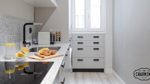 A modern kitchen with a granite countertop, a built-in oven, and a window with blinds. - Retiro Chic - One-bedroom Apartment (Madrid)