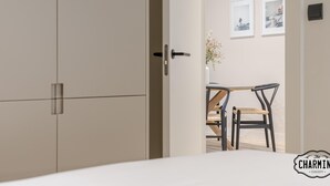 A hotel room with a bed, a wardrobe, and a dining area with a table and chairs. - Retiro Chic - One-bedroom Apartment (Madrid)