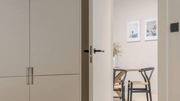 Una habitación con la puerta cerrada, una mesa de comedor con sillas y cuadros en la pared.