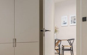 Una habitación con la puerta cerrada, una mesa de comedor con sillas y cuadros en la pared.
