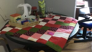 A dining area with a table covered by a patchwork tablecloth, surrounded by wicker chairs. - ENCANTO CERCA DEL AEROPUERTO - APARTAESTUDIO PEQUEÑO (Bogota)