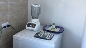 A compact kitchen with a white appliance, a blender, and a small tray with a bottle. - ENCANTO CERCA DEL AEROPUERTO - APARTAESTUDIO PEQUEÑO (Bogota)