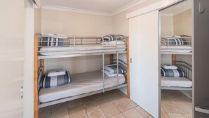 A bunk bed room with a wardrobe and a mirror.