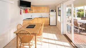 A compact kitchen with wooden cabinets, a microwave, and a dining area with a table and chairs.