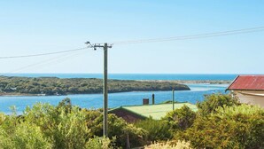 A coastal landscape with a view of the sea, a power line, and a building with a red roof.