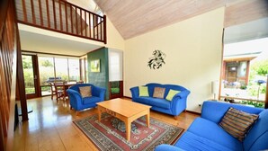 Amplia sala de estar con techo de madera, sofás azules, una mesa de centro de madera y una alfombra estampada.