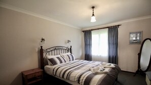 Un dormitorio con cama, mesita de noche y espejo.