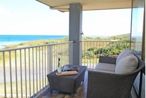 Enjoy the ocean view from this balcony with a wicker sofa and table.