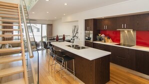 A modern kitchen with a central island, wooden staircase, and a glass railing. - Seine Bay Apartment (1 bedroom) modern accommodation in the townsite - Seine Bay Apartment (1 bedroom) (Augusta)