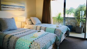 A hotel room with two beds, a large window, and a balcony with a potted plant.