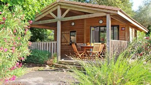 Eine Holzhütte mit einer überdachten Terrasse, einem Essbereich mit Stühlen und einem Hinweisschild, das den Standort der Hütte angibt.