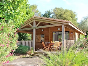 Une cabane en bois dotée d’un patio couvert, d’un coin repas avec des chaises et d’un panneau indiquant le numéro de la cabane et son emplacement.