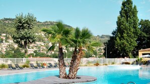 Ein Pool mit Holzterrasse, Palmen und einem weißen Zaun.