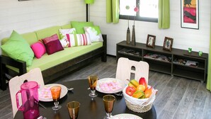 Ein gemütliches Wohnzimmer mit einem grünen Sofa, einem Esstisch mit Tellern und Gläsern sowie Bildern an den Wänden.