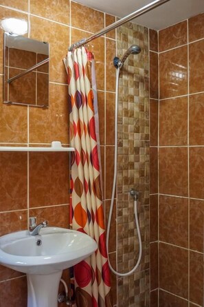 Un baño con ducha, lavamanos y espejo.
