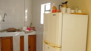 A kitchen with a white refrigerator, wooden cabinets, a sink, and a window. - La Bienvenue Rentals (Willemstad)