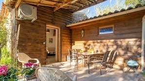 A wooden cabin with a patio area featuring a table and chairs, potted plants, and a ceiling fan. - Wonderful private villa for 6 people with A/C, WIFI, TV, terrace and pets allowed (Hyères)