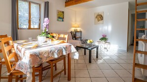 A dining area with a table set for four, a wooden staircase, and a view of the outdoors through a window. - Wonderful private villa for 6 people with A/C, WIFI, TV, terrace and pets allowed (Hyères)