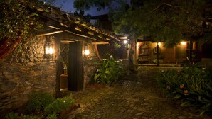 Un bâtiment en pierre doté d’une pergola en bois et d’un chemin en pierre.