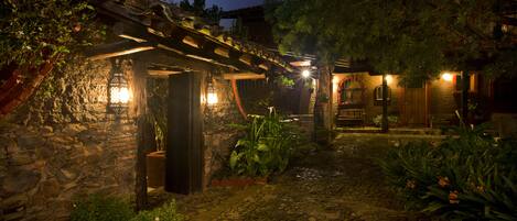 A stone building with a wooden pergola and a stone pathway.