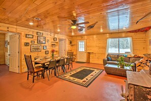A cozy cabin interior with a dining area, a sofa, and a fireplace.