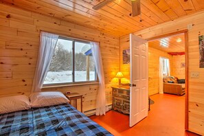 Cozy room with a bed, wooden dresser, and door leading to another space.